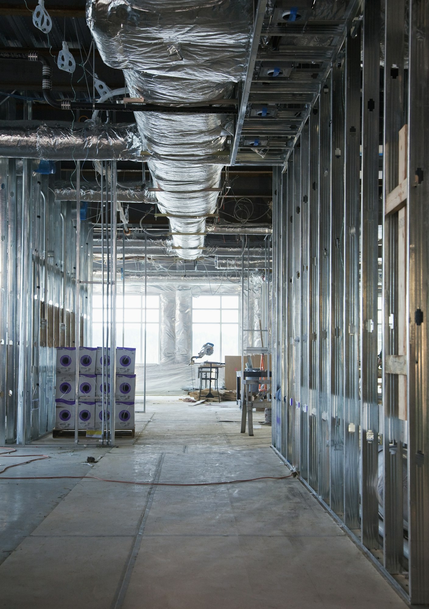 Interior of construction site with exposed ducts and metal joists.